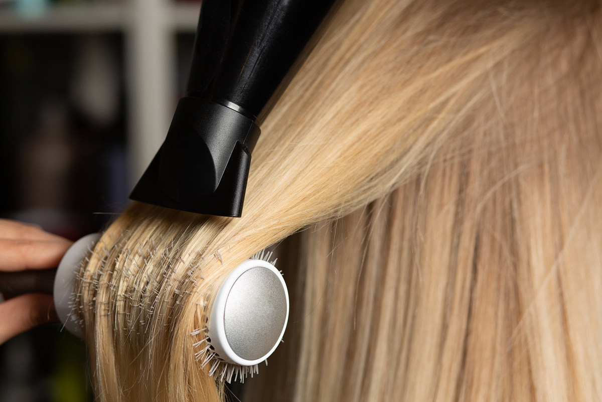 Hairdresser drying and straightening client's hair